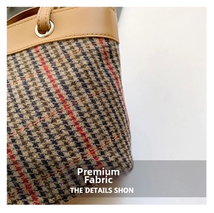 Detailed view of leather handle and plaid wool fabric on vintage bucket bag