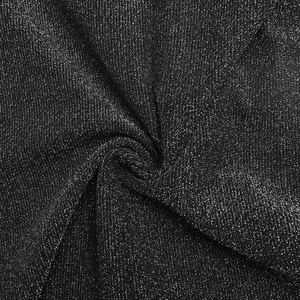 Détail du tissu noir à paillettes argentées montrant la texture et les plis doux