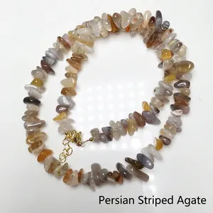 Detail of Persian Banded Agate beaded necklace with golden lobster clasp on white surface
