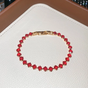 Macro shot of gold bracelet with 18k ruby gemstones on high-quality leather jewelry box