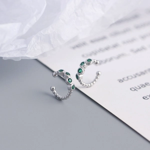 Detailed macro view of S925 silver beaded ear cuffs with four green zircon stones