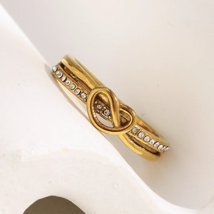 Macro detail of 18K gold plated heart infinity knot ring with clear crystal inlay