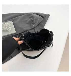 Detail view of the black tote bag interior showing silver studs and a zipper pocket