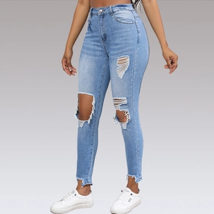 Close-up of high-waisted blue ripped jeans with distressed knees and raw hems