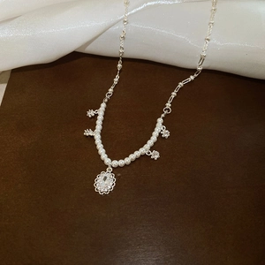 Detail of silver necklace with floral zircon pendants and white pearls on silk background