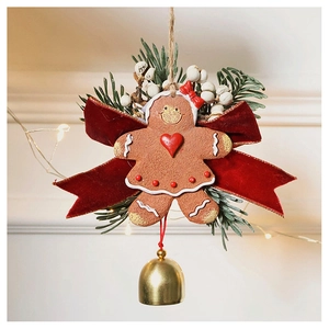 Detail of Christmas gingerbread girl ornament with red velvet bow and golden bell