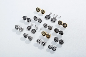 Flat lay of diverse stainless steel earrings featuring Tree of Life and Hamsa Hand symbols