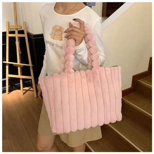 Detail of pink plush striped tote bag held by a model in a warm indoor setting