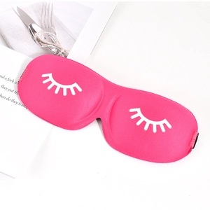 Detail of a bright pink 3D sleep mask with white eyelash print on a cozy home setting