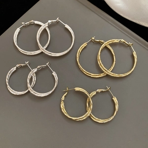 Macro shot of gold and silver textured hoop earrings in various sizes with woven finish