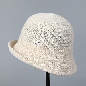 Close-up of beige knitted sun hat with intricate texture and small decorative side logo