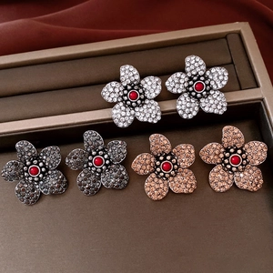 Macro shot of vintage style floral stud earrings with rhinestones and central red bead