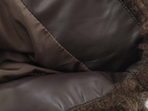 Detail of premium brown faux leather fabric with soft curly sheepskin fleece texture
