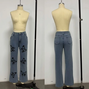 Détail des imprimés papillons noirs symétriques sur un jean évasé bleu à taille haute