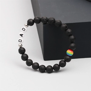 Close-up of black lava stone beads with white DAD lettering and rainbow accent