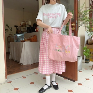 Détail du cabas en toile rose avec broderie assorti à une jupe plissée de style décontracté