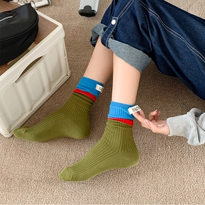 Close-up of army green ribbed crew socks with blue contrast cuff and woven fabric label