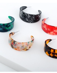 Close-up of assorted C-shaped acetate resin hoop earrings with various marble and tortoise patterns