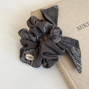Detail of charcoal gray paisley bandana hair scrunchie with BOTANI brand label