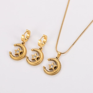 Close-up of gold star and moon jewelry set with sparkling zircon crystals on white base