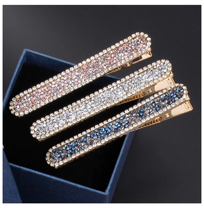Close-up of three metal hair clips with sparkling colorful rhinestones in a gift box