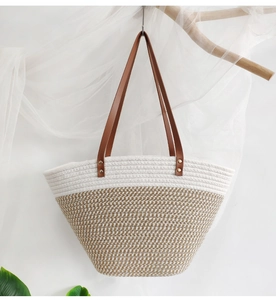 Close-up of woven cotton tote bag hanging on wooden branch with brown leather straps
