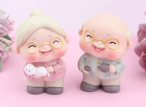 Detailed resin cake toppers of an elderly couple in traditional Chinese attire with cat and teapot