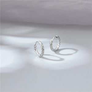 Minimalist silver hoop earrings with hammered metal texture on light gray background