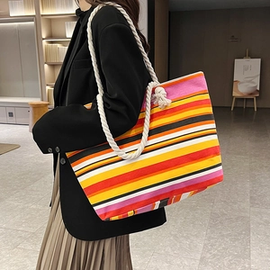 Large colorful striped canvas tote bag with thick rope handles shown on shoulder