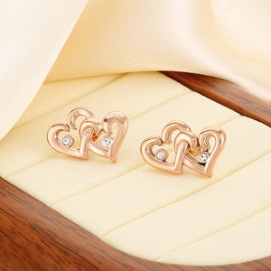 Macro detail of rose gold interlocking heart stud earrings with sparkling crystals