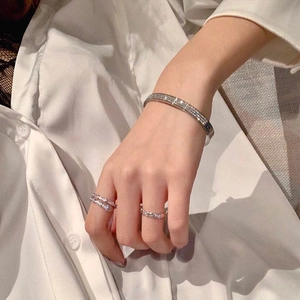 Detailed view of silver pavé crystal bangle and matching rings on a white silk sleeve