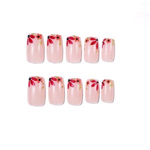 Short square pink press-on nails with red flower patterns and gold foil flakes detail