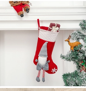 Christmas stocking with grey gnome and gift box hung on a fireplace mantel