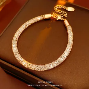 Luxurious gold mesh bracelet filled with white crystals on a brown leather jewelry box