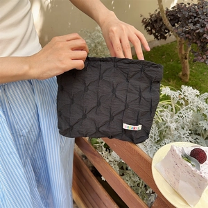 Vista lifestyle di una pochette trapuntata nera con etichetta colorata sozakka