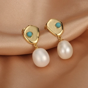 Detail of 18K gold-plated earrings with large drop pearls and turquoise stone on silk