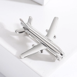 Close-up of a minimalist silver airplane brooch with a polished metallic finish