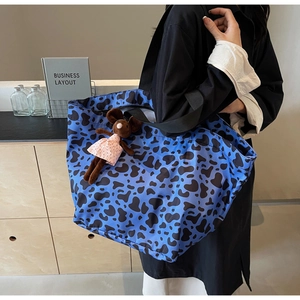 Close-up of blue cow print canvas tote bag with a cute mouse plush charm on shoulder