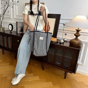 Detail of black and white checkered canvas tote bag with long shoulder strap and embroidery