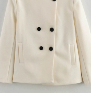 Detailed macro view of double-breasted buttons and side pockets on cream wool coat
