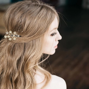 Close-up of a model wearing a gold star-shaped hair clip with sparkling rhinestones
