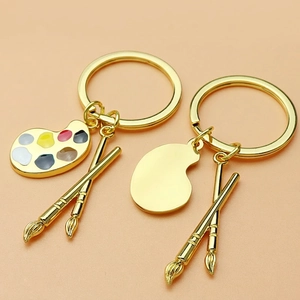 Art palette keychain with paint brushes in gold finish and colorful enamel detail
