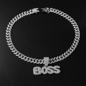 Macro shot of silver hip-hop BOSS pendant with cubic zirconia on a black background
