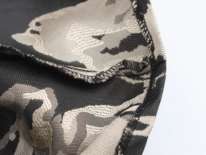 Detail shot of black and beige camouflage knit fabric with precise overlock stitching edge