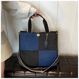 Détail d'un sac cabas en denim bicolore avec garnitures dorées et bandoulière amovible