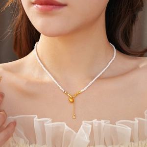 Close-up of pearl necklace with gold gourd pendant and zircon drop on neck