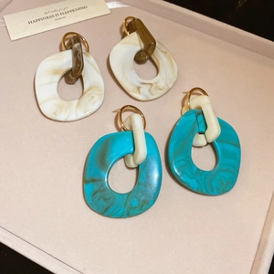 Irregular acrylic resin hoop earrings with cream and teal marble texture on pink velvet