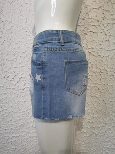 Detail van lichtblauwe denim shorts met sterrenprint en distressed gescheurde franjeranden