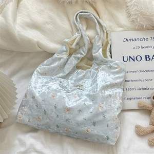 Detail of light blue velvet tote bag featuring pink bear prints and a woven textile label