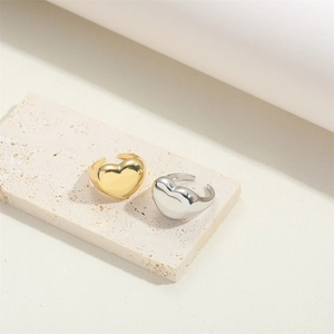 Adjustable heart-shaped vintage rings in gold and silver finish on travertine stone
